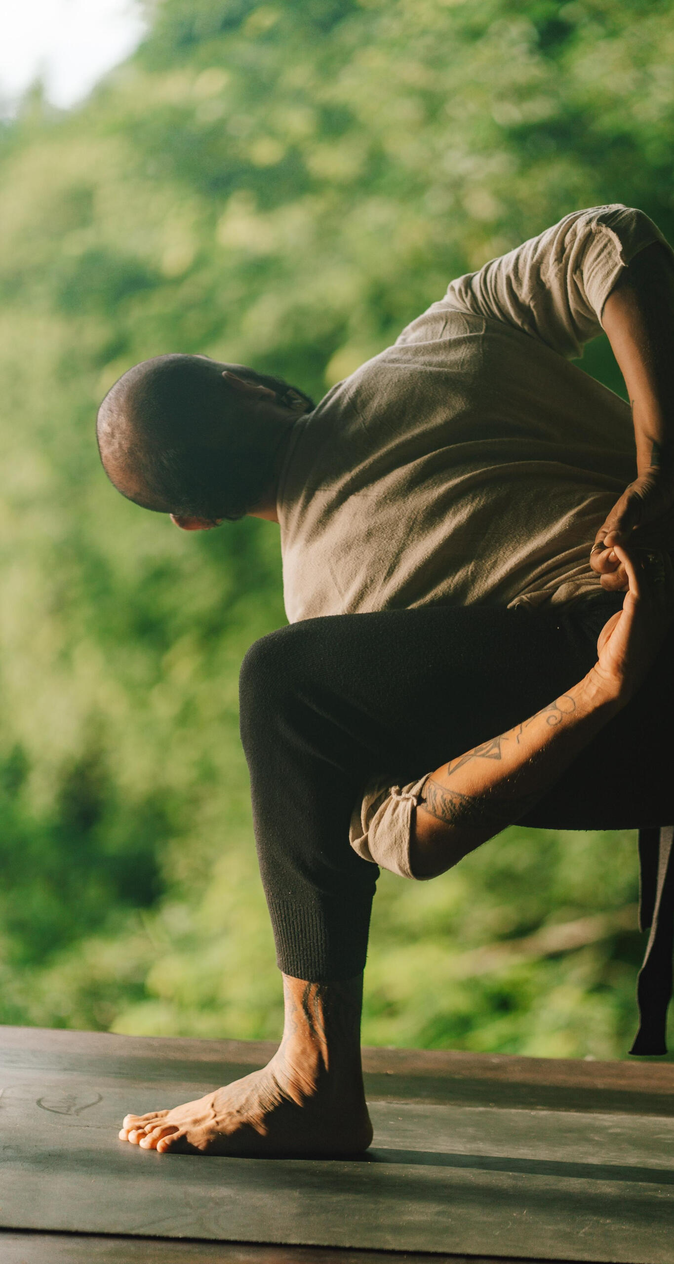 Warrior Pose Variation with arm wrap in Tropical Garden Setting in Lombok Free Lopez performing a creative variation of Warrior Pose in a lush tropical environment, wrapping his arms around his bent front thigh to deepen the stretch and embody strength, grounding, and focus.